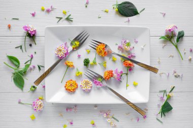 Beyaz çatallı, plakalı ve arka plan olarak kullanılabilir küçük çiçekli masa