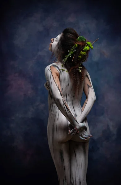 Studio portrait of woman painted on body, body paint with nature  drawing