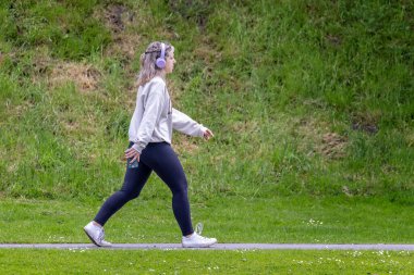 24 Mayıs 2022 'de Warminster, Wiltshire, İngiltere' de kulaklık takan ve cep telefonu taşıyan genç çekici bir kadın.