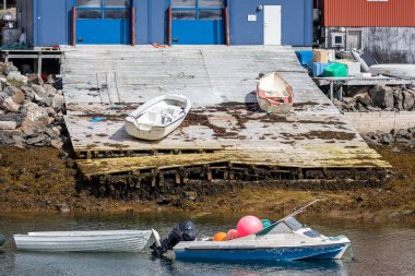 Fishing boats moored on dilapidated wooden pier in Maniitsoq, Greenland on 15 July 2022