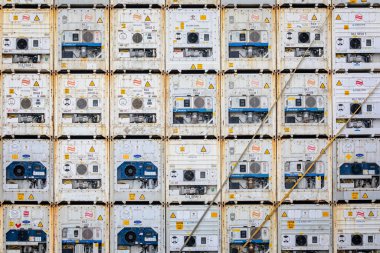 Grid of rear end of 28 white shipping containers with air conditioning units  stacked  in 4 deep and 7 wide in Sisimiut, Greenland on 16 July 2022