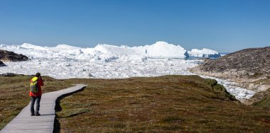 Wooden walkway through the arctic tundra  leading to the Ilulissat icefjord in Ilulissat, Greenland on 17 July 2022