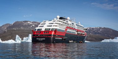 Close up of Hurtigruten's MS Fridtjof Nansen expedition cruise ship amidst icebergs with zodiacs off loading in Disko Bay, Greenland on 18 July 2022