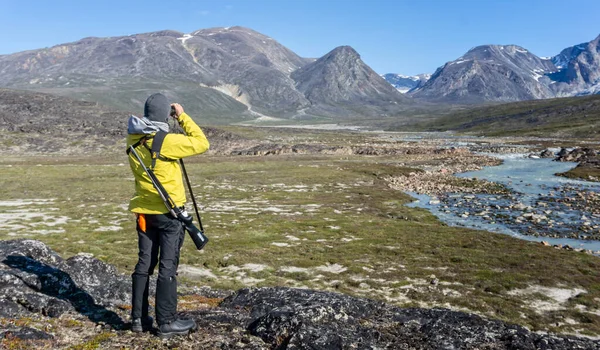 Male lookout armed with rifle scanning for polar bears in the tundra at Camp Frieda on the Disko Bay coast, Greenland on 18 July 2022