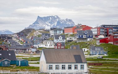 Multi coloured houses set against a snow covered mountain backdrop in Nuuk, Greenland on 20 July 2022