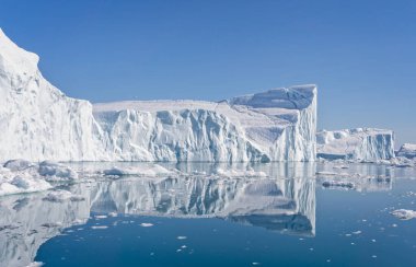 Büyük buz dağları ve Grönland 'daki Ilulissat Icefjord' undaki yansımaları.