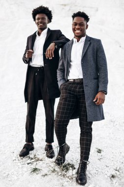 İki modaya uygun Afrikalı siyah adam, kayalık dağların arka planında, şık klasik kıyafetler içinde, şık saç stili, yakışıklı erkekler, model portre, moda konsepti, erkek giyimi