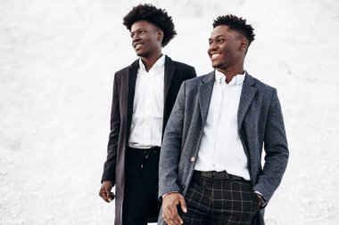 İki modaya uygun Afrikalı siyah adam, kayalık dağların arka planında, şık klasik kıyafetler içinde, şık saç stili, yakışıklı erkekler, model portre, moda konsepti, erkek giyimi