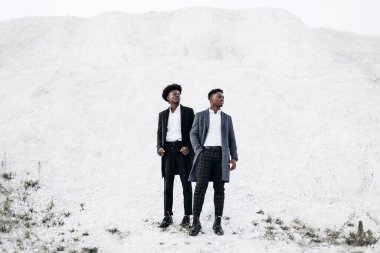 Sokakta poz veren iki mutlu siyahi adam, klasik siyah takım elbiseli arkadaşlar, moda, erkek giyim, alışveriş,