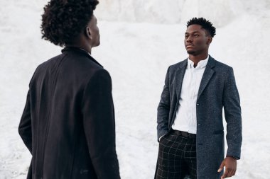 Sokakta poz veren iki mutlu siyahi adam, klasik siyah takım elbiseli arkadaşlar, moda, erkek giyim, alışveriş,