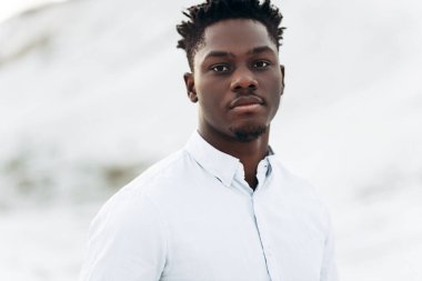 Beyaz gömlekli, şık, şık, Afro-Amerikan bir adamın portresi. Dağın arka planında poz veren şık bir adam.