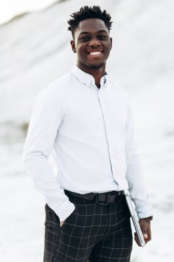 Beyaz gömlekli, şık, şık, Afro-Amerikan bir adamın portresi. Dağın arka planında poz veren şık bir adam.