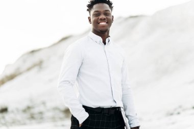 Beyaz gömlekli, şık, şık, Afro-Amerikan bir adamın portresi. Dağın arka planında poz veren şık bir adam.