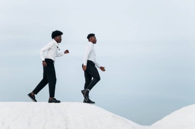 İki zarif, kendine güvenen Afro-Amerikan işadamı dağın zirvesine tırmanıyor, İşadamı dağa tırmanıyor, Başarı ve liderlik konsepti.