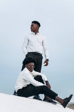 İki Afrikalı Amerikalı, dağın zirvesinde, kayalara tırmanıyor, iş adamı başarısı, dağın zirvesinde yürüyüş, kazanan lider konsepti.