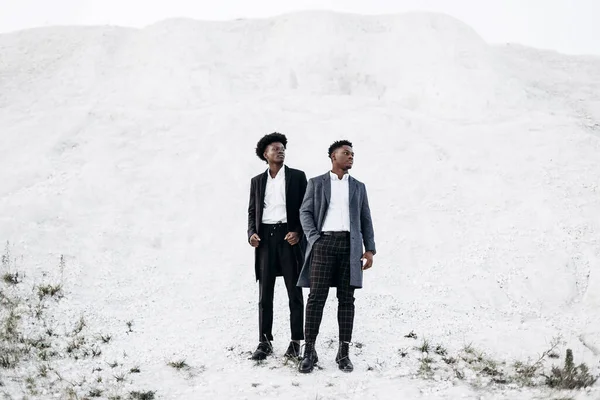 Sokakta poz veren iki mutlu siyahi adam, klasik siyah takım elbiseli arkadaşlar, moda, erkek giyim, alışveriş,