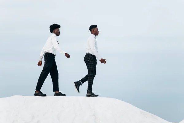 Two fashionable business elegant confident African American men, climb the mountain reaching the top of the mountain, Business man climbs the mountain, Success and leadership business concept