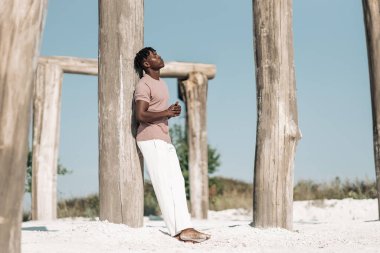 Yakışıklı, şık siyah kıvırcık adam, şık kıyafetler giyen adam, kuru çölde poz veren, vahşi batı tarzı, model