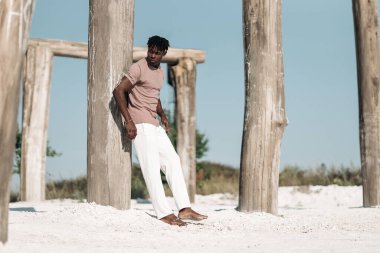 Yakışıklı, şık siyah kıvırcık adam, şık kıyafetler giyen adam, kuru çölde poz veren, vahşi batı tarzı, model