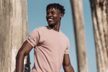 Yakışıklı, kıvırcık saçlı, Afrikalı erkek, moda mankeni, açık havada gülümseyen şık siyah adam.