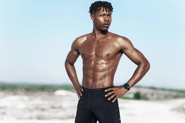 Portrait African American man, fitness athlete, with a muscular naked torso, on a sunny day outdoors in nature, sports, motivation, healthy lifestyle