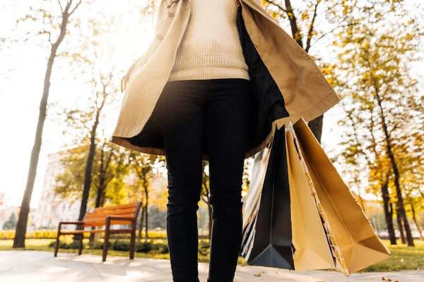 妇女手牵着购物袋在街上的特写镜头 穿着米黄色雨衣和秋鞋的妇女 季节性购物概念 — 图库照片