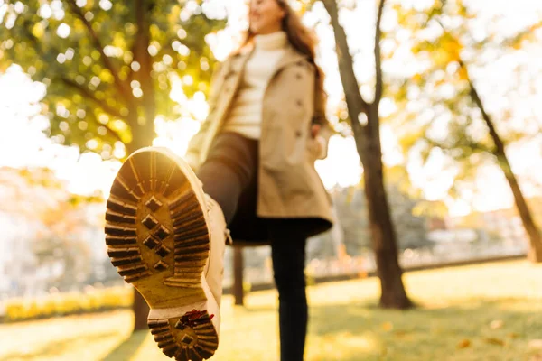 一个女人的秋鞋在一个黄叶林立的公园里散步时的特写 穿着米黄色雨衣的女人 — 图库照片