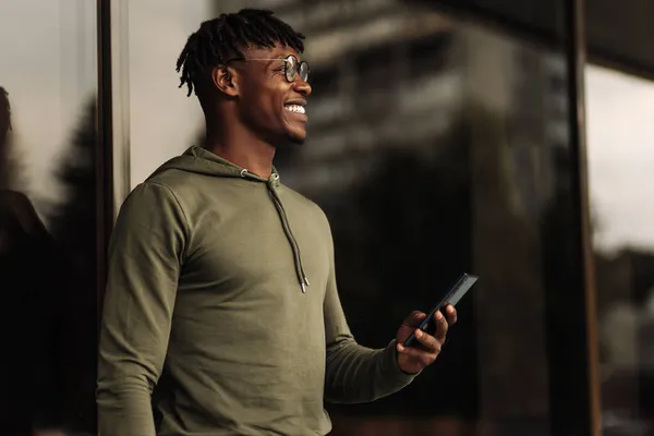 Bello Sorriso Riccio Uomo Africano Utilizzando Telefono Cellulare Mentre Piedi — Foto Stock