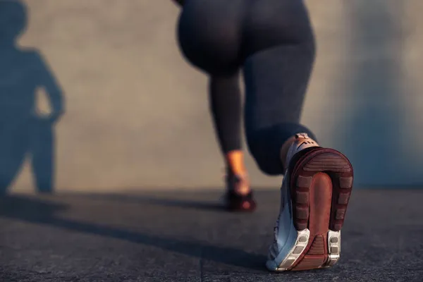 Fitness woman doing lunges exercises for training leg muscles, active girl doing lunge exercise on one leg front forward for buttocks, on gray wall background