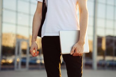 Elinde evrak çantası ve dizüstü bilgisayarı olan bir adam. Şehirdeki adam, arka plandaki cam binanın arka planına karşı.