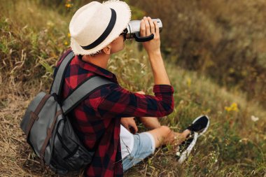 Sırt çantalı bir yürüyüşçü dağın tepesinde oturur ve kıyı manzarasının tadını çıkarır. Elinde bir fincan kahveyle bir kayanın üzerinde oturan genç bir adam çevresindeki doğa manzarası ile birlikte. Dağ ve sahil yolculuğu