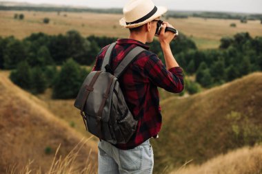 Sırt çantalı bir yürüyüşçü dağın tepesinde oturur ve kıyı manzarasının tadını çıkarır. Elinde bir fincan kahveyle bir kayanın üzerinde oturan genç bir adam çevresindeki doğa manzarası ile birlikte. Dağ ve sahil yolculuğu