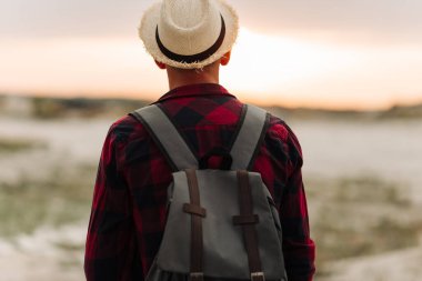Arkaya bakan, şapkalı gezgin, ellerini dağın tepesindeki patikaya kaldırıyor, arkadan bakıyor. Yüksek kayalıkların tepesinde bir turist. Özgürlük, seyahat, zafer konsepti