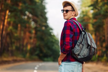 Ormanda yolda yürüyen şapkalı bir turistin portresi. Ormanda sırt çantasıyla dolaşan güçlü bir sporcu.