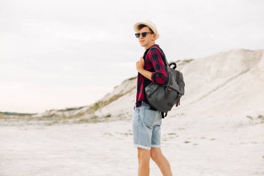 Şapkalı ve sırt çantalı bir gezgin dağ yolunda tek başına İskandinav dağlarında yürüyüş yapıyor. Aktif sağlıklı yaşam tarzı, macera yolculuğu tatili