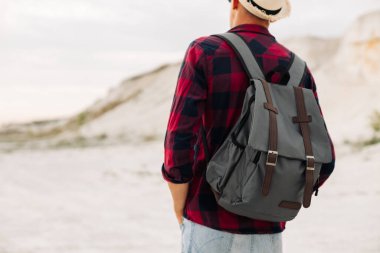 Sırt çantalı erkek hippi gezgin harika dağ ve vadi manzarası için sabırsızlanıyor. Yaz tatilinin tadını çıkaran bir adam doğa yürüyüşünde eğleniyor.