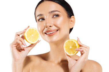 Kadın ve meyve portresi. Mutlu bir manken yüzüne yakın sulu bir portakal tutar ve beyaz arka plandaki kameraya bakar. Güzel bir kız sağlıklı cilt için narenciye ve doğal vitaminler kullanır.