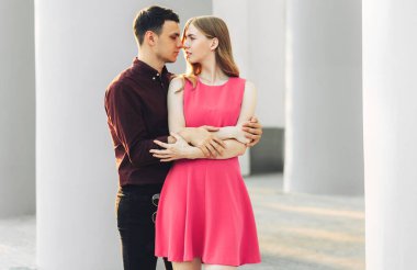 Güzel romantik bir çift, açık havada, elbiseli çekici genç bir kadın ve yakışıklı bir erkek sarılıp birbirlerine bakıyorlar. Sevgililer Günün kutlu olsun.