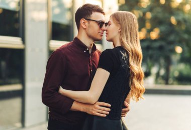 Güzel romantik bir çift, açık havada, elbiseli çekici genç bir kadın ve yakışıklı bir erkek sarılıp birbirlerine bakıyorlar. Sevgililer Günün kutlu olsun.