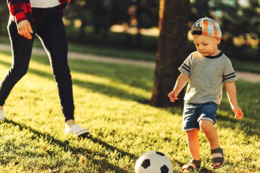 Güneşli bir günde futbol sahasında futbol oynayan küçük bir çocuğun yakın çekimi. Anaokulu çocuklarının sağlıklı boş vakitleri