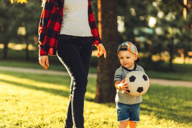 Güneşli bir günde futbol sahasında futbol oynayan küçük bir çocuğun yakın çekimi. Anaokulu çocuklarının sağlıklı boş vakitleri