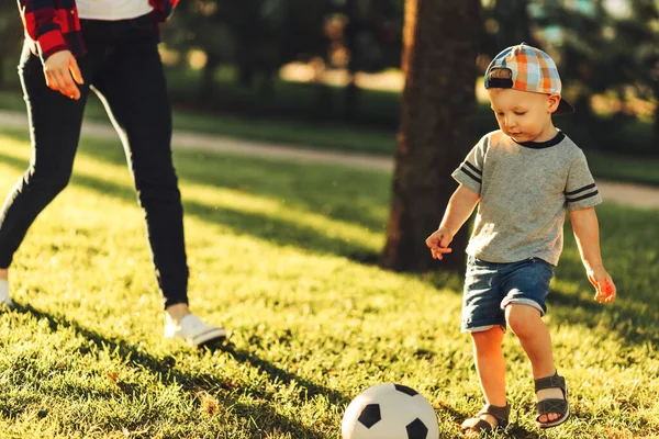Güneşli bir günde futbol sahasında futbol oynayan küçük bir çocuğun yakın çekimi. Anaokulu çocuklarının sağlıklı boş vakitleri