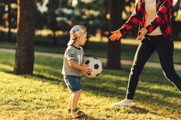 Mutlu bir aile. Güneşli bir yaz gününde anne ve oğlu çimlerin üzerinde futbol oynarken eğleniyorlar. Anne ve çocuk parkta oynuyorlar. Aile parkta futbol oynuyor, Anneler Günü.