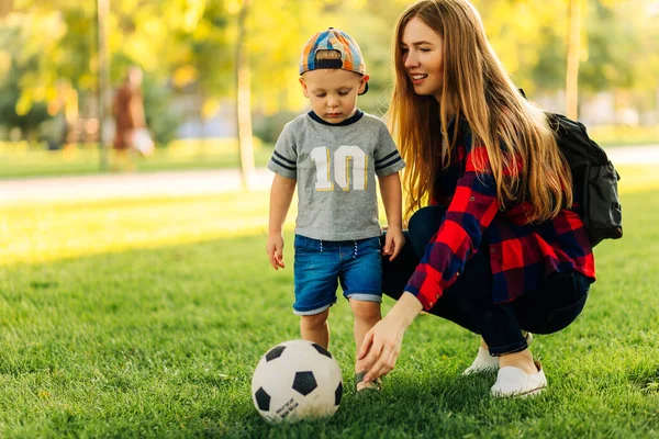 Happy family play football in summer, Mother and son play and run in the park on a beautiful morning. A boy kicks football while playing with his family. Family concept