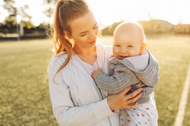 Aile, çocuklar ve mutlu insanlar konsepti. Mutlu anne dışarıda oynar, sarılır ve oğlunu öper. Mutlu kadınlar günü. Aile tatili ve birlik.