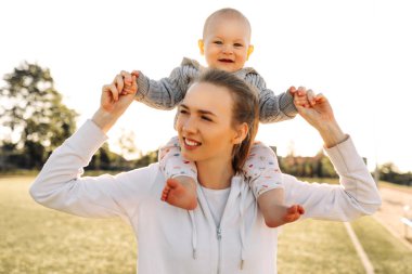 Anneler Günü. Sevimli küçük oğlu olan sevimli, genç bir anne. Sevgi dolu bir aile. Anne ve bebek dışarıda oynuyor, öpüşüyor ve sarılıyorlar. Anneler Günü, 8 Mart, aile tatili ve birliktelik kavramı..