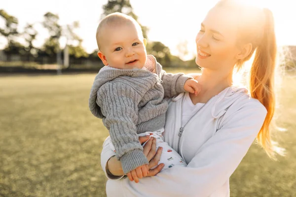 Anne ve çocuğun portresi, dışarıda çocuğunu kucaklayan gülen genç bir anne. Anne ve çocuğu baharın erken zamanlarının tadını çıkarıyorlar, anne ve küçük çocuk kucaklaşıyorlar, anneler gününü birlikte kutluyorlar.
