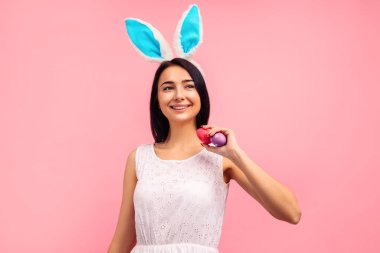 Paskalya yumurtası boyanmış tavşan kulaklı mutlu kadın stüdyoda pembe arka planda. Yüksek kalite fotoğraf