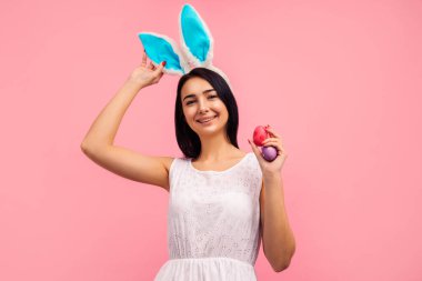 Tavşan kulaklı güzel ve pozitif esmer kadın ve boyalı Paskalya yumurtalarıyla Paskalya yumurtaları, göz, paskalya, stüdyoda pembe arka planda. Yüksek kalite fotoğraf