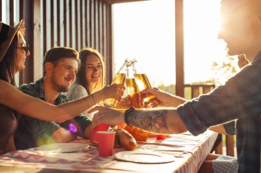 Bir piknik sırasında barbekü için toplanan neşeli arkadaşlar masada eğleniyorlar. Arkadaşlar eğlenir, yer, içer. Güneşli bir günde doğada toplandılar.